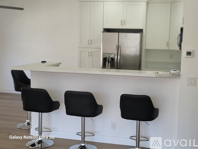 A kitchen with a white counter and black bar stools.
