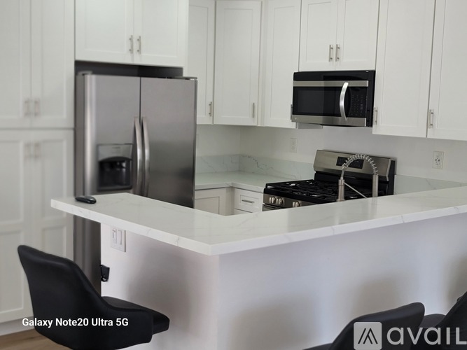 A kitchen with a white countertop and a black chair.
