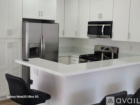 A kitchen with a white countertop and a black chair.