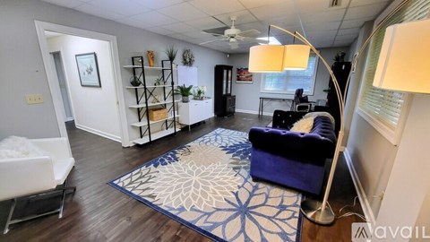 A living room with a blue rug and a white chair.