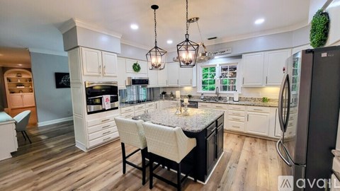 A modern kitchen with a center island and pendant lights.