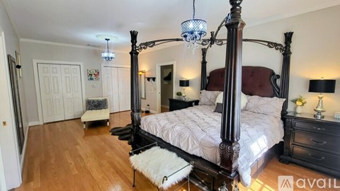 A bedroom with a four poster bed and a white rug.