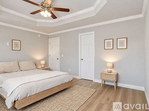 A bedroom with a bed, a ceiling fan, and two nightstands with lamps.