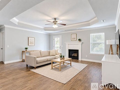 A living room with a beige couch, a fireplace, and a ceiling fan.