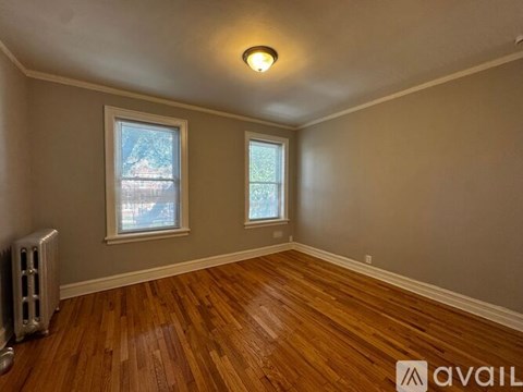 A room with wooden floors and two windows.