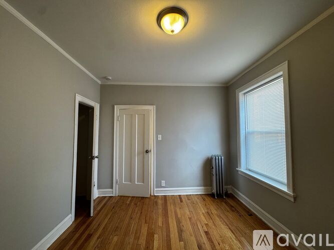 A room with a wooden floor and a window with blinds.
