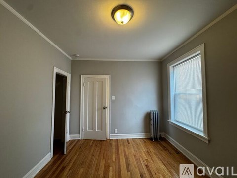 A room with a wooden floor and a window with blinds.
