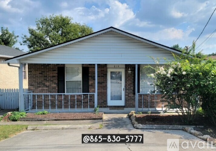 A small house with a porch and a white picket fence.