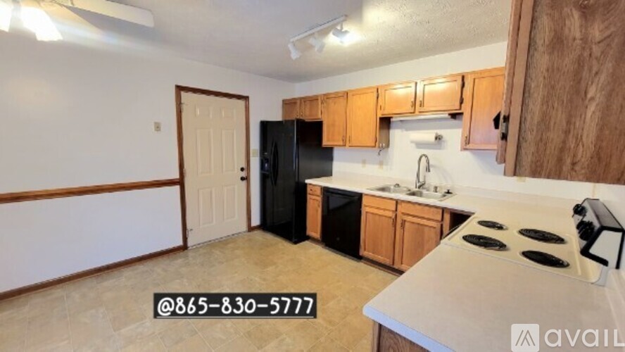 A kitchen with black appliances and wooden cabinets is available for rent.