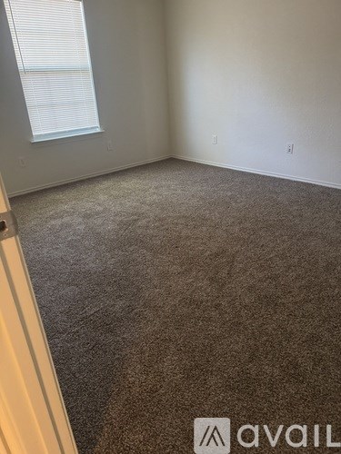 A carpeted room with a window and Avail logo.