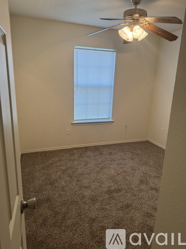 A room with a carpeted floor, a ceiling fan, and a window with blinds.