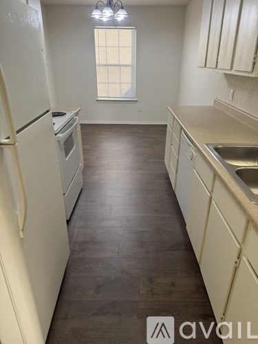 A kitchen with white appliances and wooden floors.