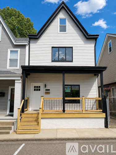 A house with a white door and a black awning is for sale.