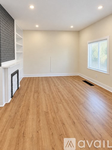 A room with wooden flooring and a window with blinds.