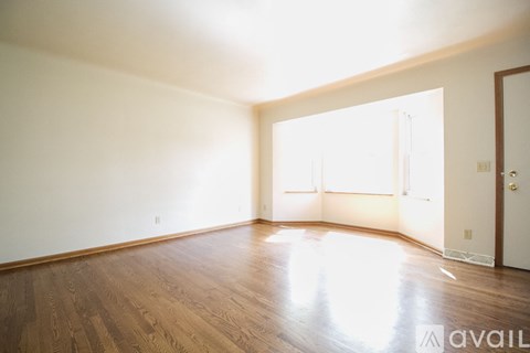 A room with wooden floors and a door on the right side.
