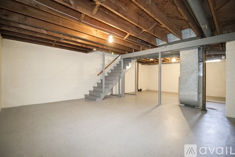 A spacious room with a staircase and wooden ceiling.