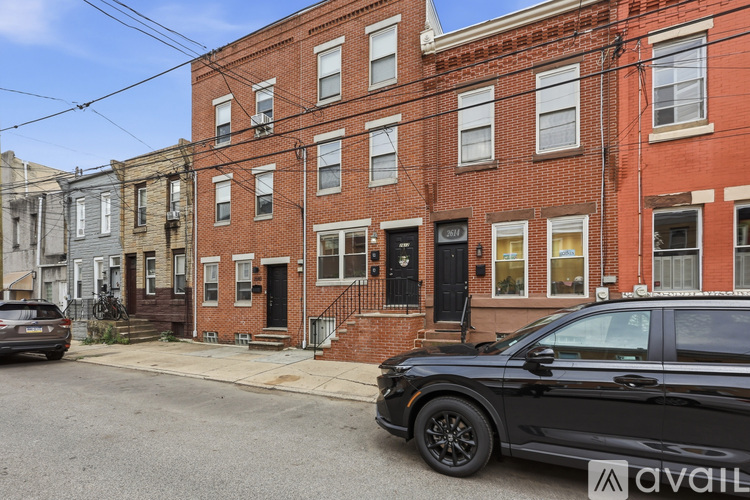 A black car is parked in front of a brick building with a sign that reads "available.".