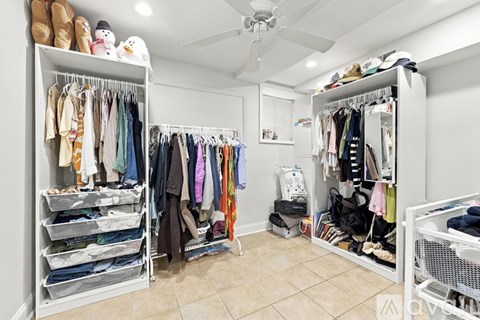 A spacious walk-in closet with clothes and shoes organized on shelves and hangers.