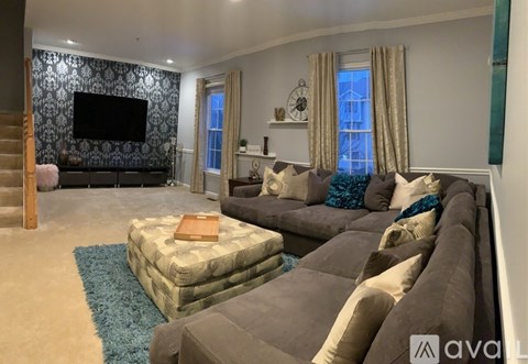 A living room with a grey sofa and a television on the wall.