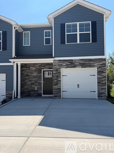 A two-story house with a garage door and a stone wall.