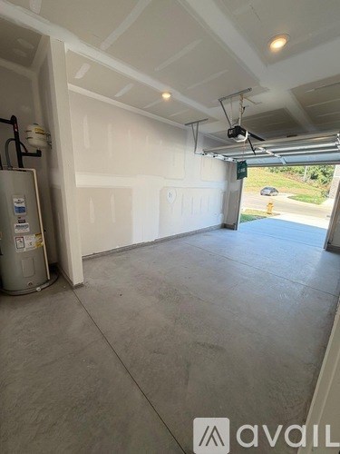 A large empty room with a trash can and a white door.