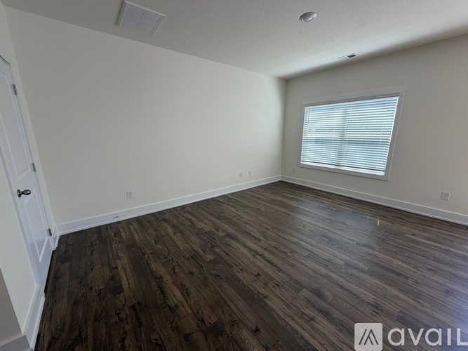 A room with wooden flooring and a window with blinds.