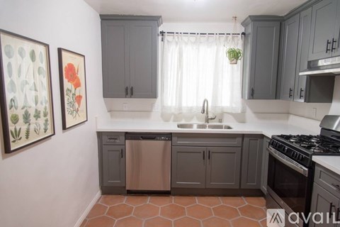 A kitchen with a stove, sink, and cabinets.