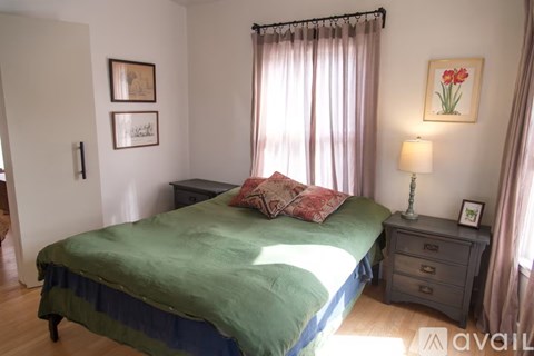 A bedroom with a bed, nightstand, and two pictures on the wall.