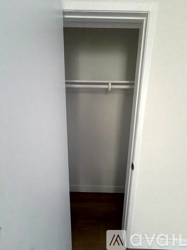 A white closet with a shelf and a door.