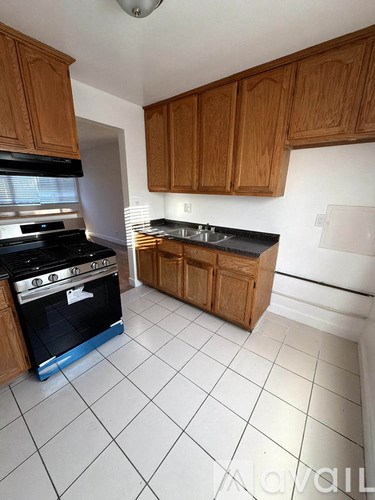 A kitchen with a black stove top oven and wooden cabinets.