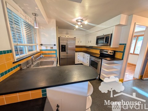 A kitchen with a black counter top and a tile backsplash.