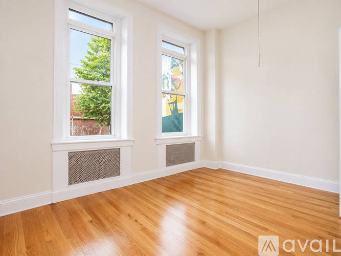 A room with wooden floors and two windows.
