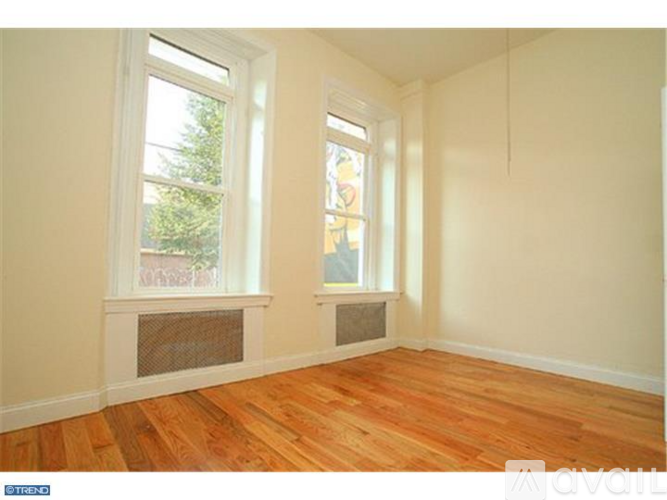 A room with wooden floors and two windows.