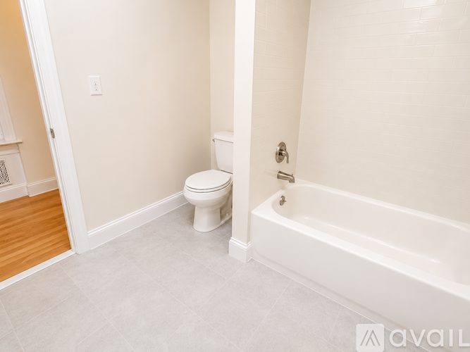 A white toilet sits in a bathroom next to a bathtub.