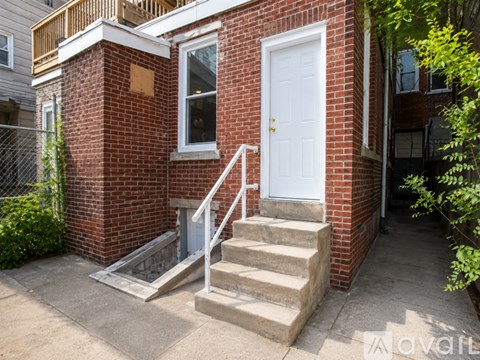 A small red brick house with a white door and a white staircase.