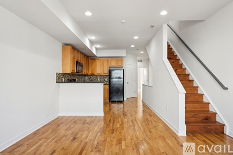 A spacious room with wooden floors and a staircase leading to another level.