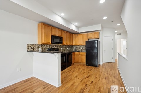 A kitchen with wooden cabinets and a black refrigerator.