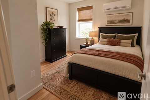 A bedroom with a large bed and a black dresser with a plant on top.
