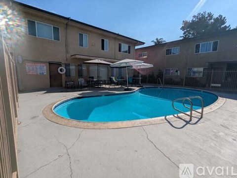 A swimming pool in a backyard with a sun umbrella and a building in the background.