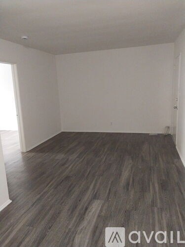 A room with wooden flooring and white walls.