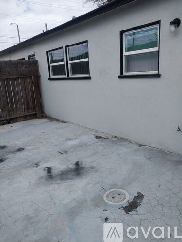 A white house with a grey roof and a grey concrete patio.