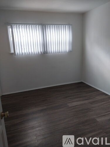 A room with wooden flooring and a window with blinds.