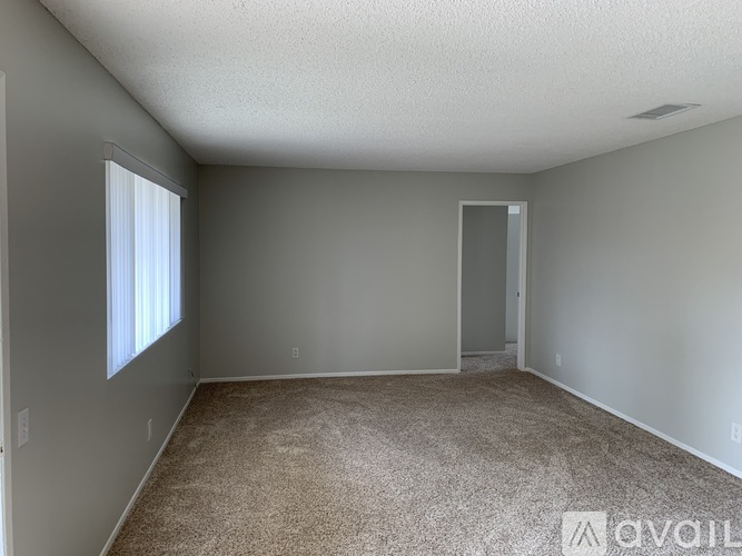 A room with a carpeted floor and a doorway leading to another room.