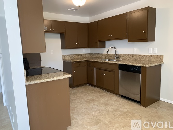 A kitchen with brown cabinets and a granite countertop.