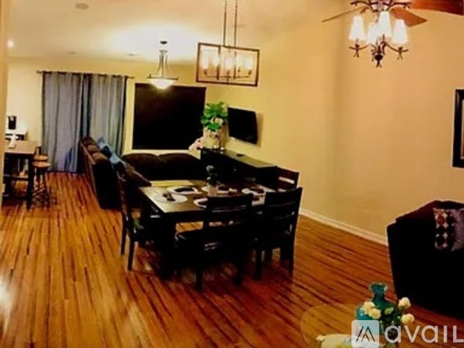 A living room with a black couch and a wooden floor.