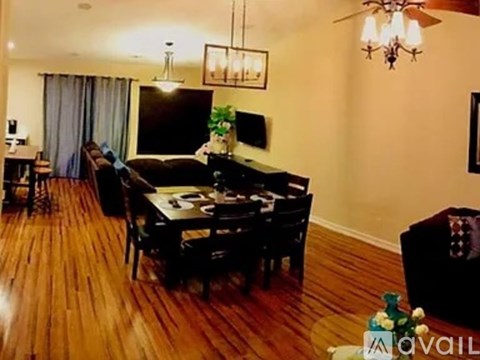 A living room with a black couch and a wooden floor.