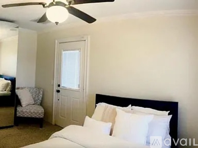 A bedroom with a bed, chair, and ceiling fan.