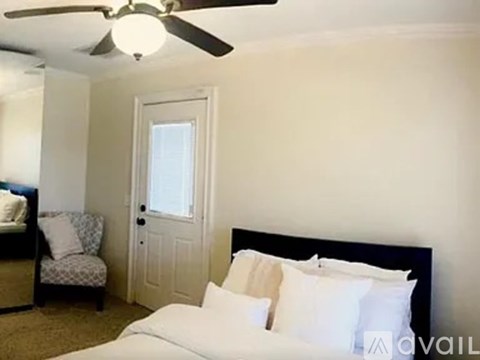 A bedroom with a bed, chair, and ceiling fan.