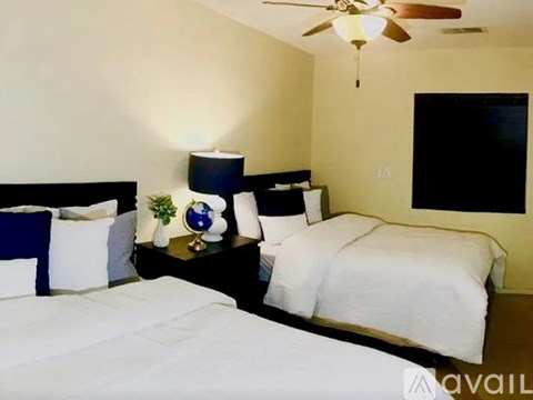A bedroom with two beds, a ceiling fan, and a small table with a plant and a globe on it.