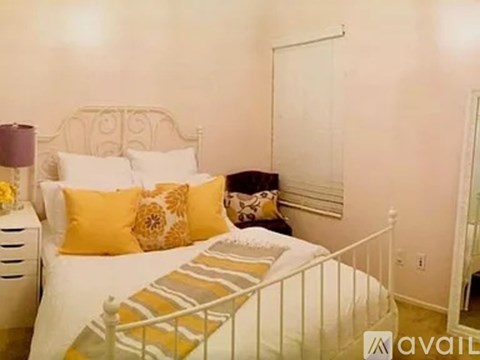 A bedroom with a white bed and yellow pillows.